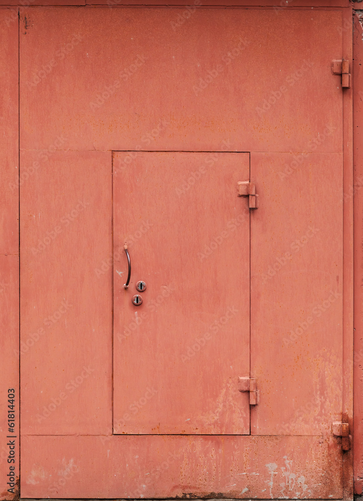 Fototapeta premium Red metal garage wall with locked door. Background texture