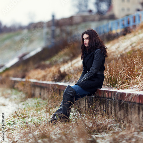 Lonely girl sitting looking into the distance in winter coat