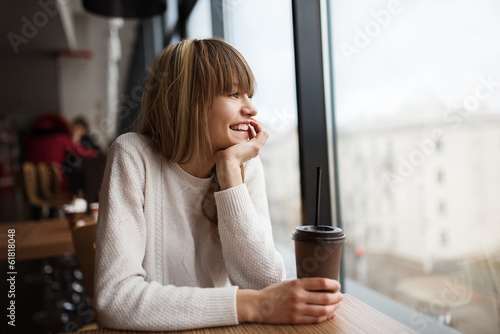 Beautiful cute girl in the cafe near the window with coffee