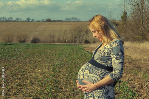 Sad pregnant woman in a field, week 38
