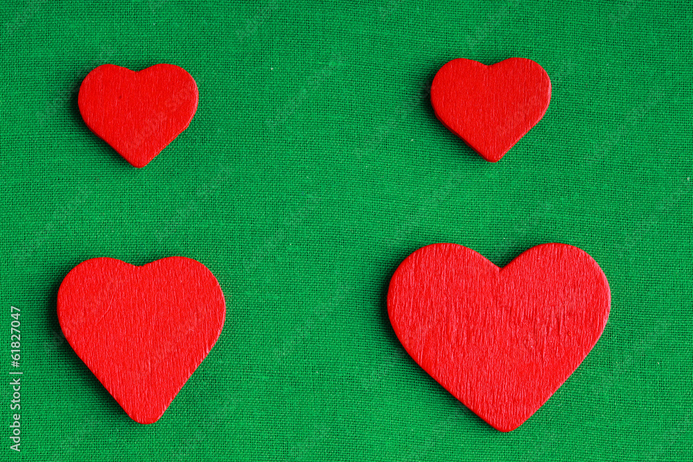 Red wooden decorative hearts on green cloth background Red wooden decorative hearts on green cloth background