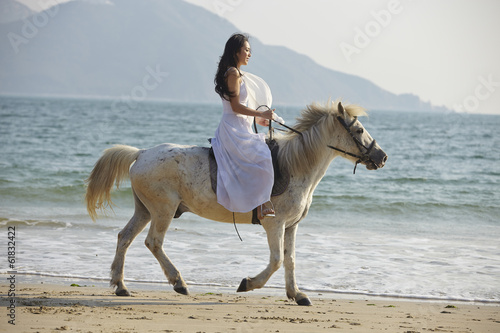 a woman riding horse on beach