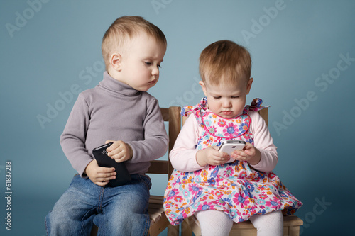 Fototapeta little boy and girl playing with mobile phones