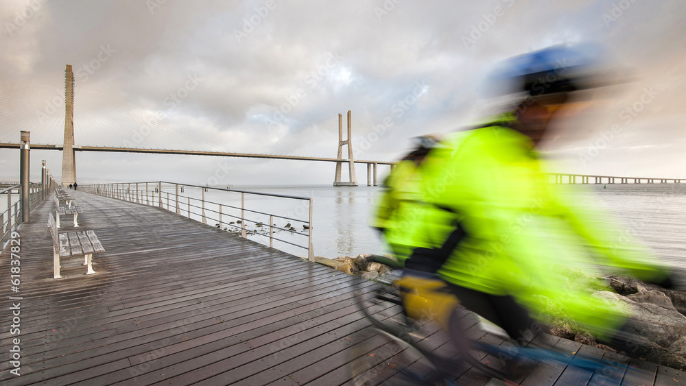 Blurred bicycle riders on promenade in front of of Vasco da Gama Blurred bicycle riders on promenade in front of of Vasco da Gama