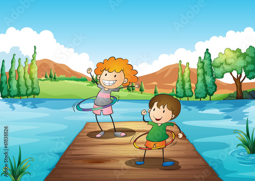 Two kids playing hulahoop at the river