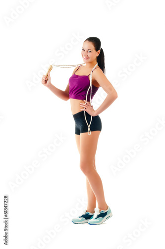 young woman with jump rope on shoulder stand sideways in sportsw