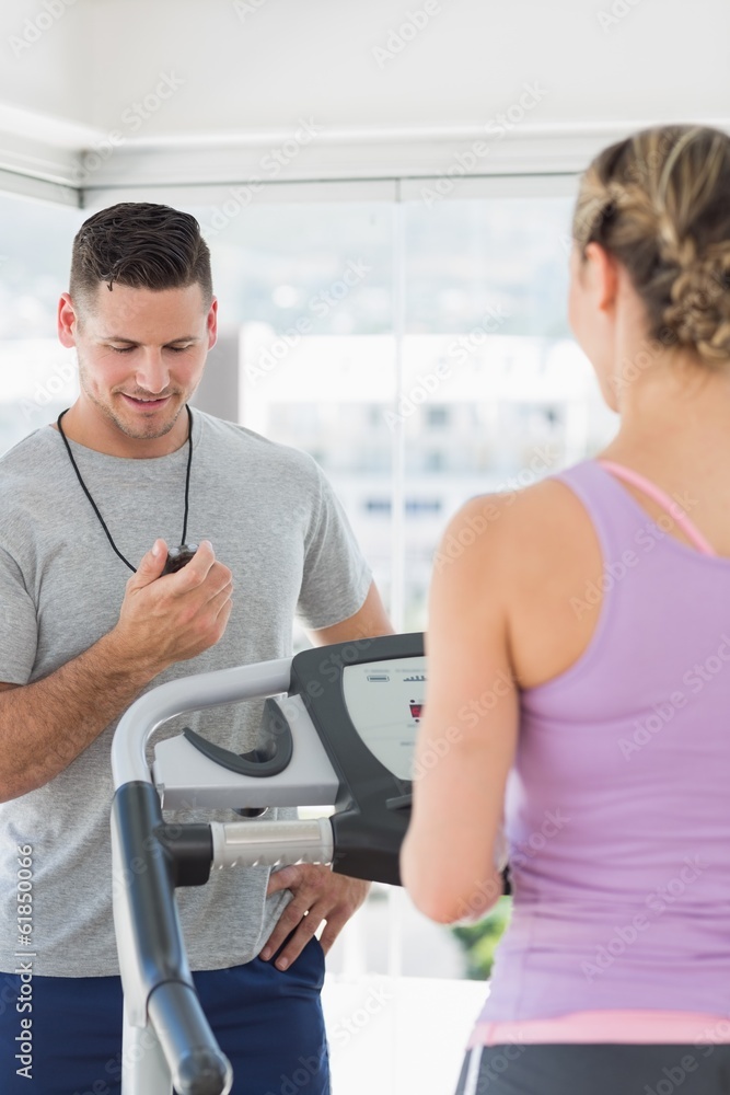 Trainer watching woman exercising at gym Trainer watching woman exercising at gym