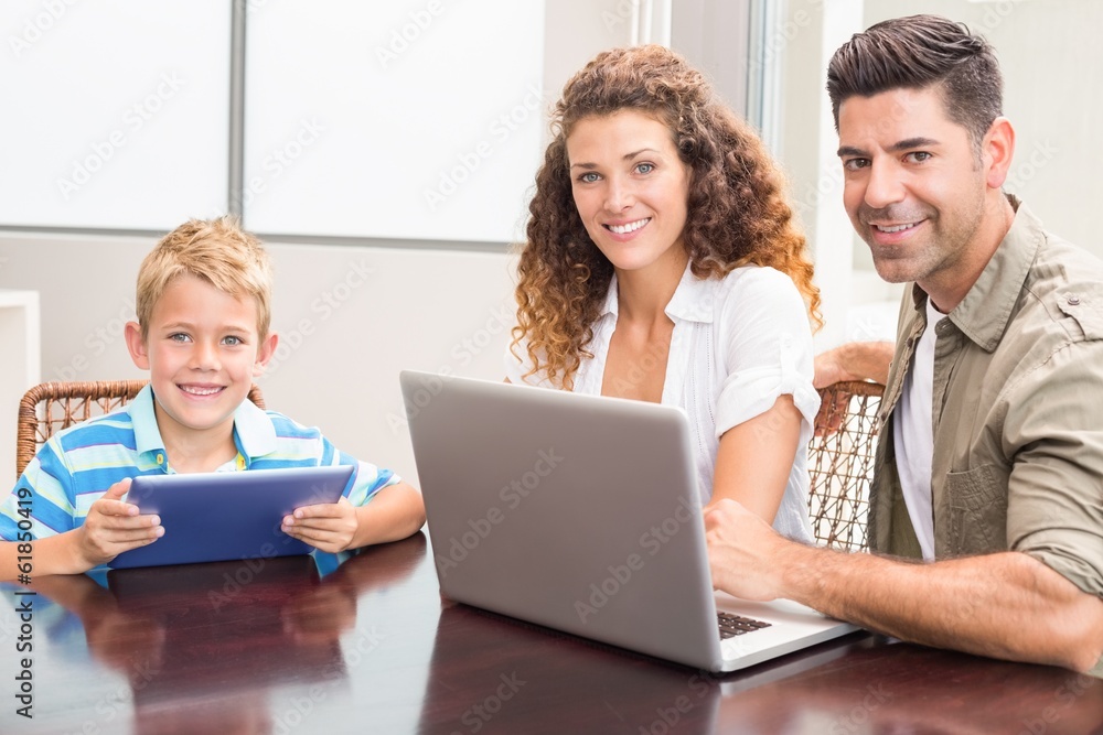 Happy parents sitting with son using tablet and laptop Happy parents sitting with son using tablet and laptop