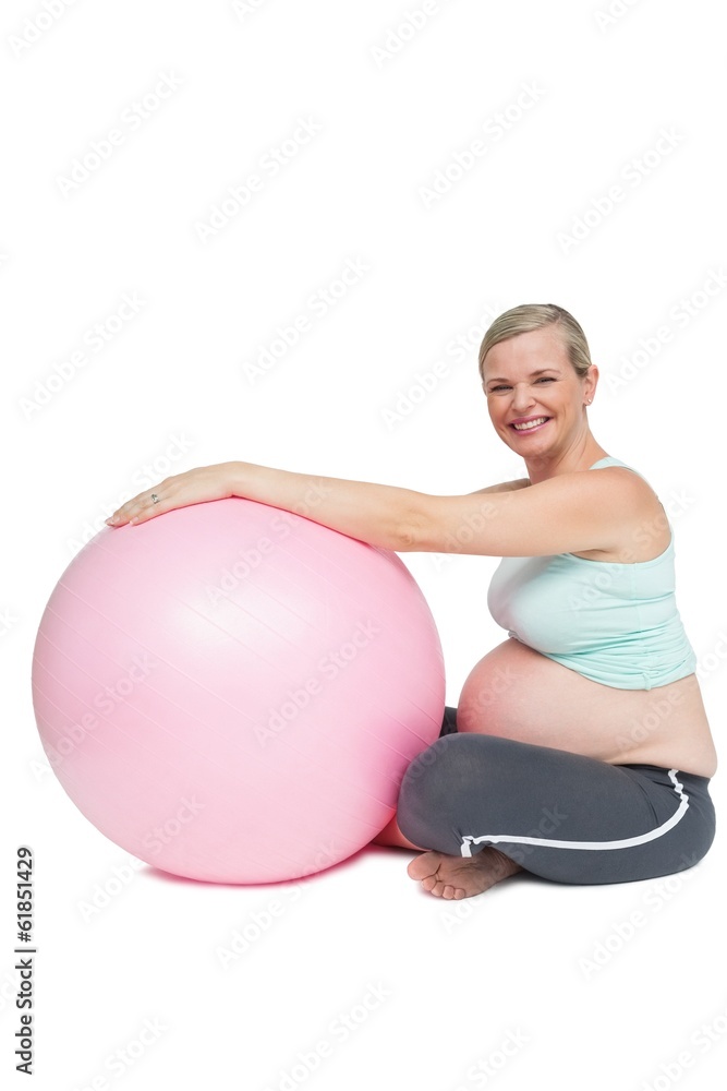 Cheerful pregnant woman leaning against pink exercise ball Cheerful pregnant woman leaning against pink exercise ball
