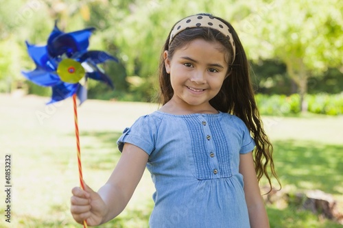 Slika na platnu Cute little girl holding pinwheel at park