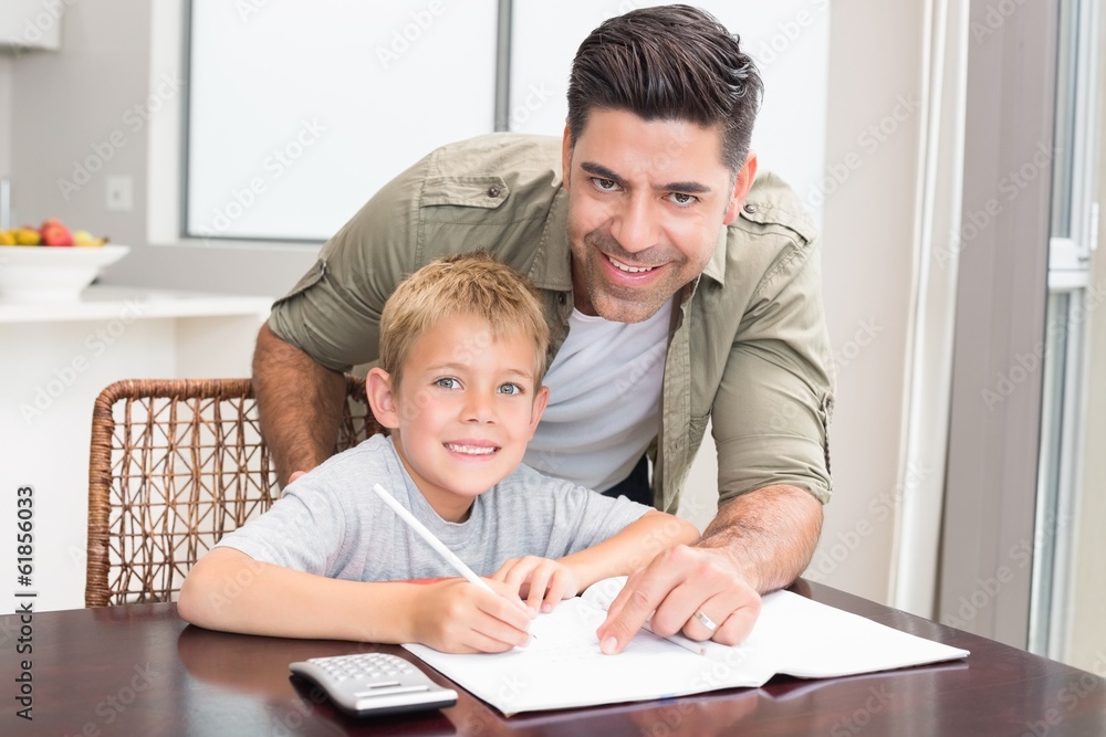 Cheerful father helping son with math homework at table Cheerful father helping son with math homework at table