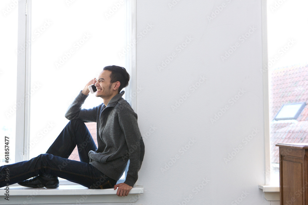 Young man laughing on mobile phone at home Young man laughing on mobile phone at home