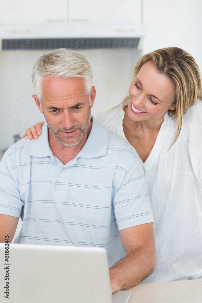 Smiling couple using laptop together at the counter Smiling couple using laptop together at the counter