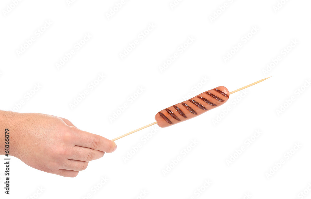 Sausage roll grilled on stick in hand.