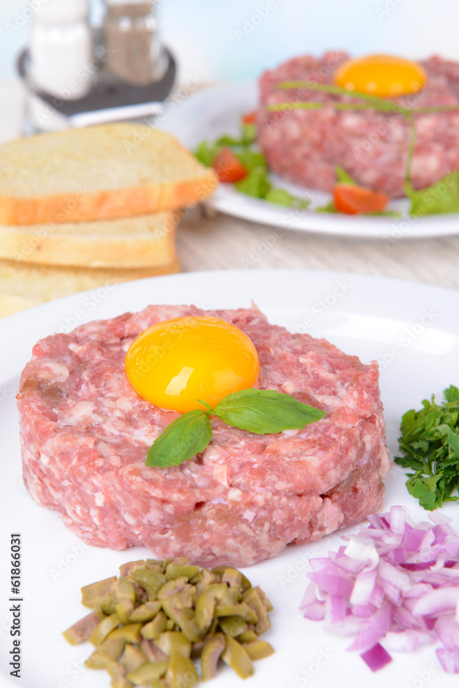 Delicious steak tartare with yolk on plate on table close-up