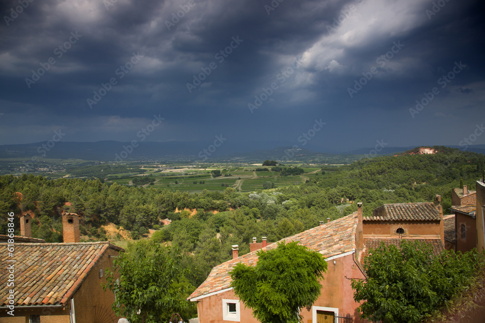 Houses and trees in Provence, with dark, stormy sky