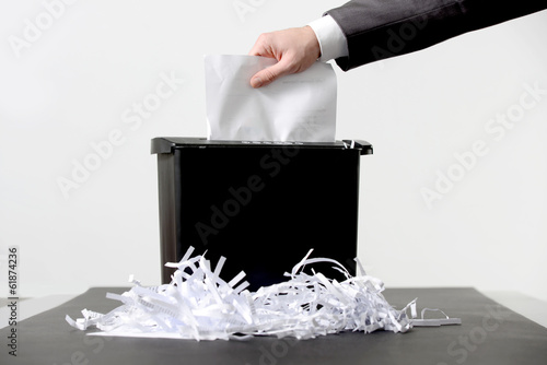 Hand of businessman putting a document in paper shredder