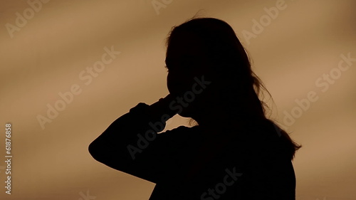 Female silhouette goes with her hands through her hair