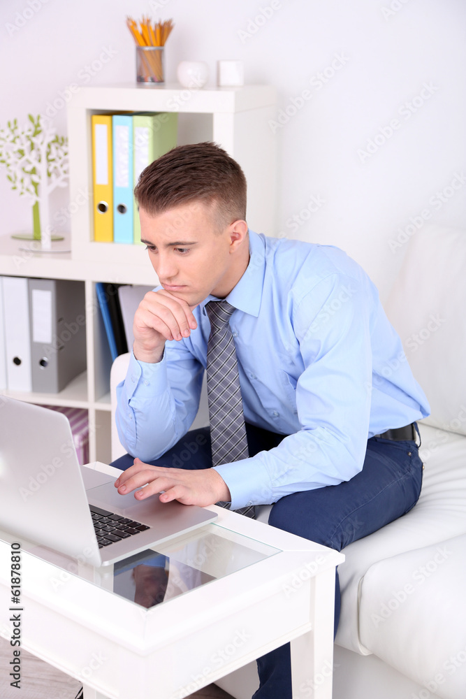 Handsome young man working on laptop at home