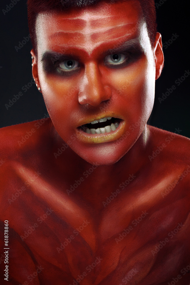 Portrait of a handsome young man in a red body painting Portrait of a handsome young man in a red body painting
