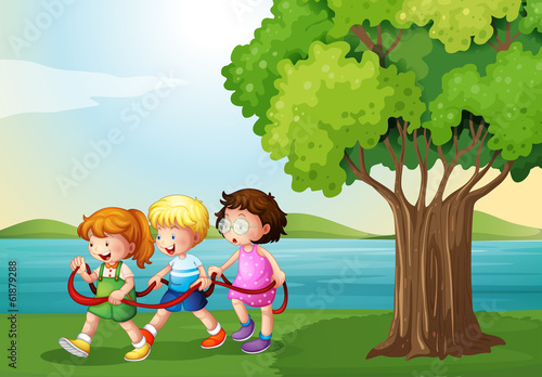 Three kids playing with the rope near the river