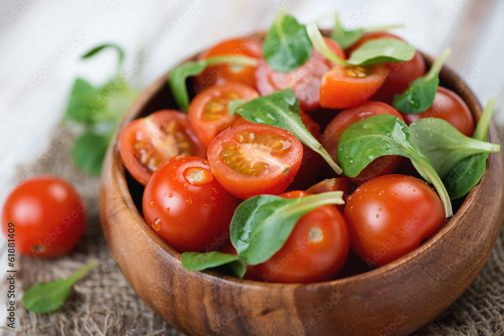Wooden bowl with fresh cherry tomatoes and corn salad, close-up Wooden bowl with fresh cherry tomatoes and corn salad, close-up