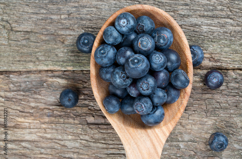 fresh blueberries in a wooden spoon over wooden table