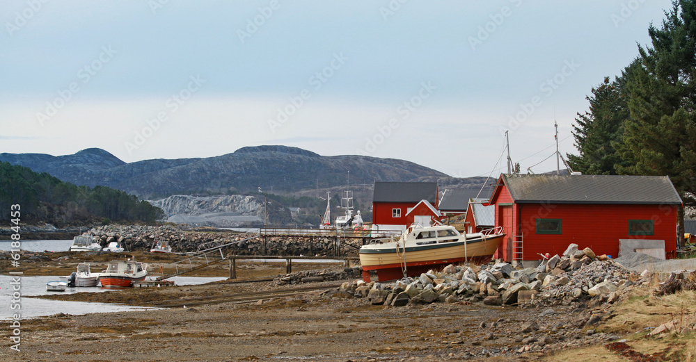 Norwegian red wooden houses and small fishing boats on the coast