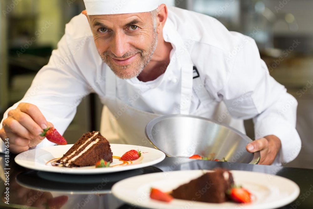 Smiling male pastry chef decorating dessert in kitchen Smiling male pastry chef decorating dessert in kitchen