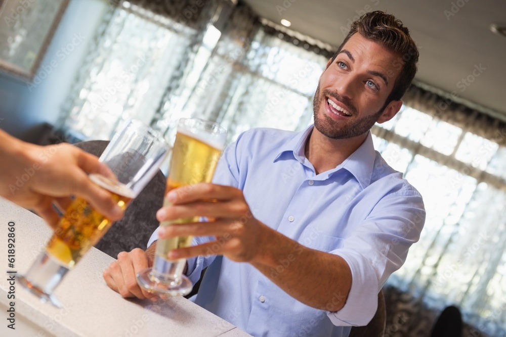 Smiling businessman clinking glass of beer with bartender Smiling businessman clinking glass of beer with bartender