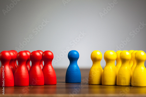 Single blue pawn figure between red and yellow groups photo