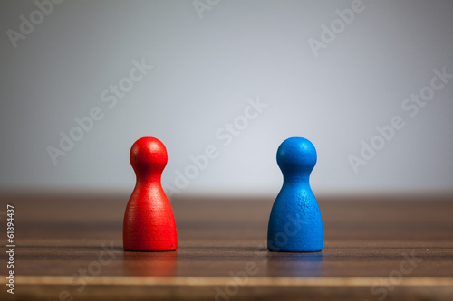 Red and blue pawn figurines  table  grey background