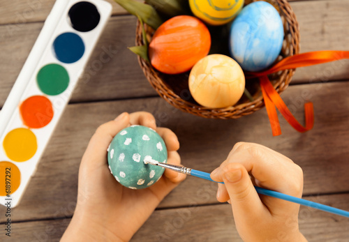 Child paints egg for Easter, focus on eggs