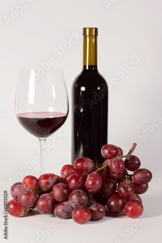 Calice di vino con bottiglia e uva rossa isolato su bianco