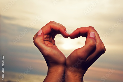 Hand making a heart shape. Sea sunset