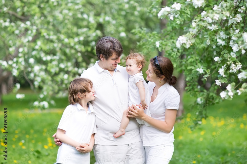 Beautiful young family in a blooming apple tree garden