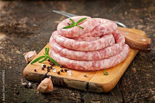 Fotografiet Fresh raw sausage on the old wooden background