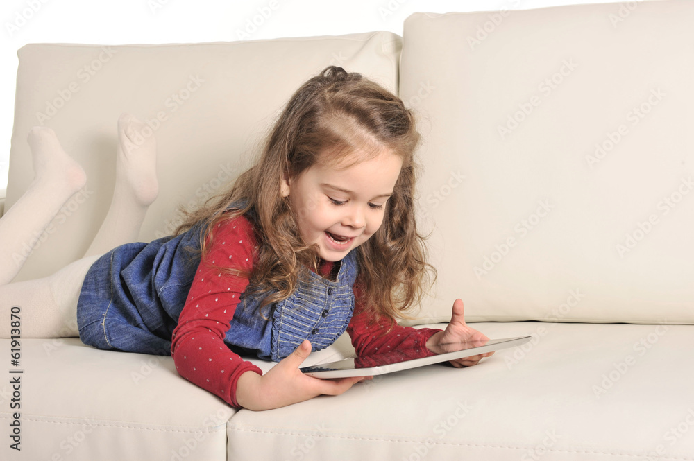Sweet Little Girl lying on Couch playing with Digital Pad Sweet Little Girl lying on Couch playing with Digital Pad