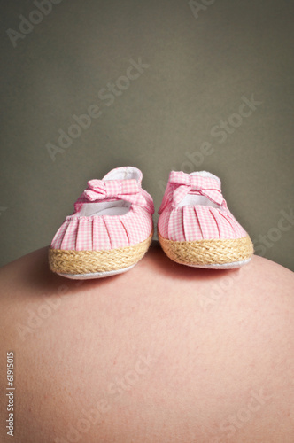 Little baby shoes on a pregnant stomach