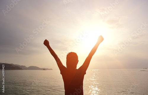 cheering woman open arms to sunrise seaside