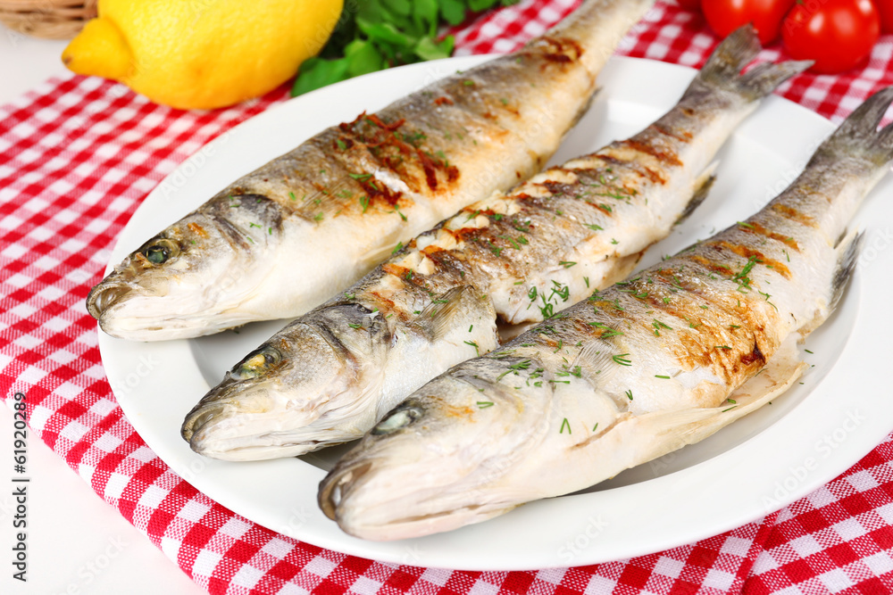 Delicious grilled fish on plate on table close-up Delicious grilled fish on plate on table close-up