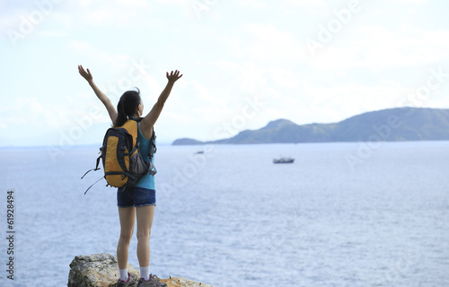 hiking woman open arms seaside rock