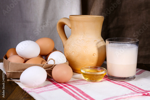 Eggnog with milk and eggs on table and fabric background