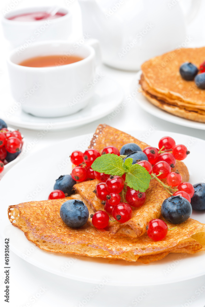 Breakfast with pancakes, fresh berries and black tea on white Breakfast with pancakes, fresh berries and black tea on white