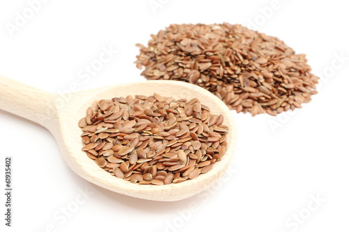 Heap of linseed with wooden spoon on white background