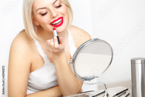 Red lips. Beautiful Woman Doing Daily Makeup. Lipstick applying