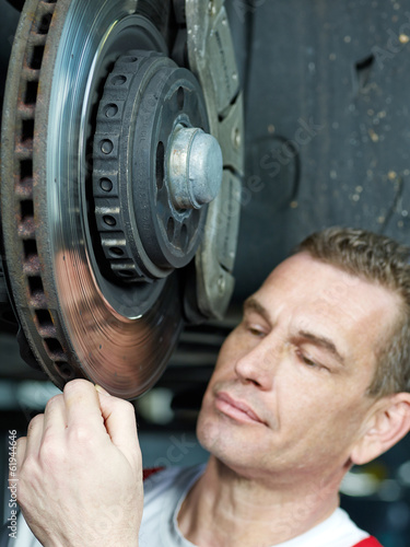 Car mechanic in a garage repairs a brake