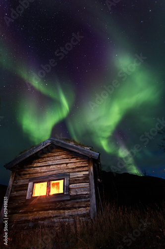 old wooden hut with northern lights photo