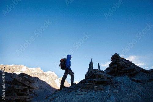 silhouette of hiker climbing mountain peak at sunrise