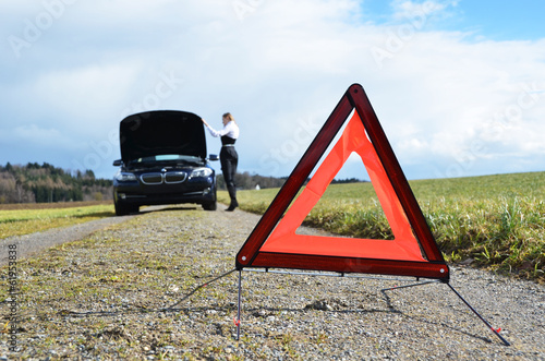 Broken car, girl and warning triangle